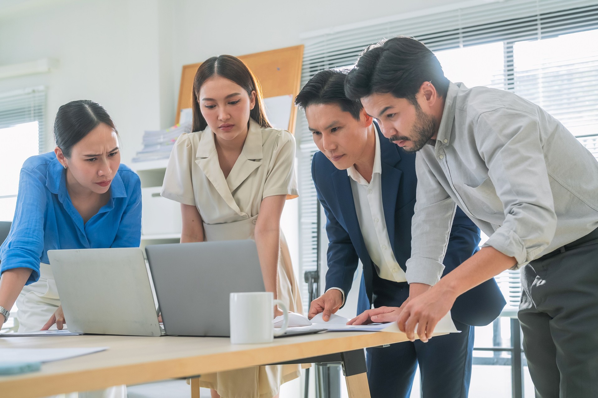 Business team standing in meeting, analyzing charts and laptop data, brainstorming financial strategy for company growth, planning goals for success